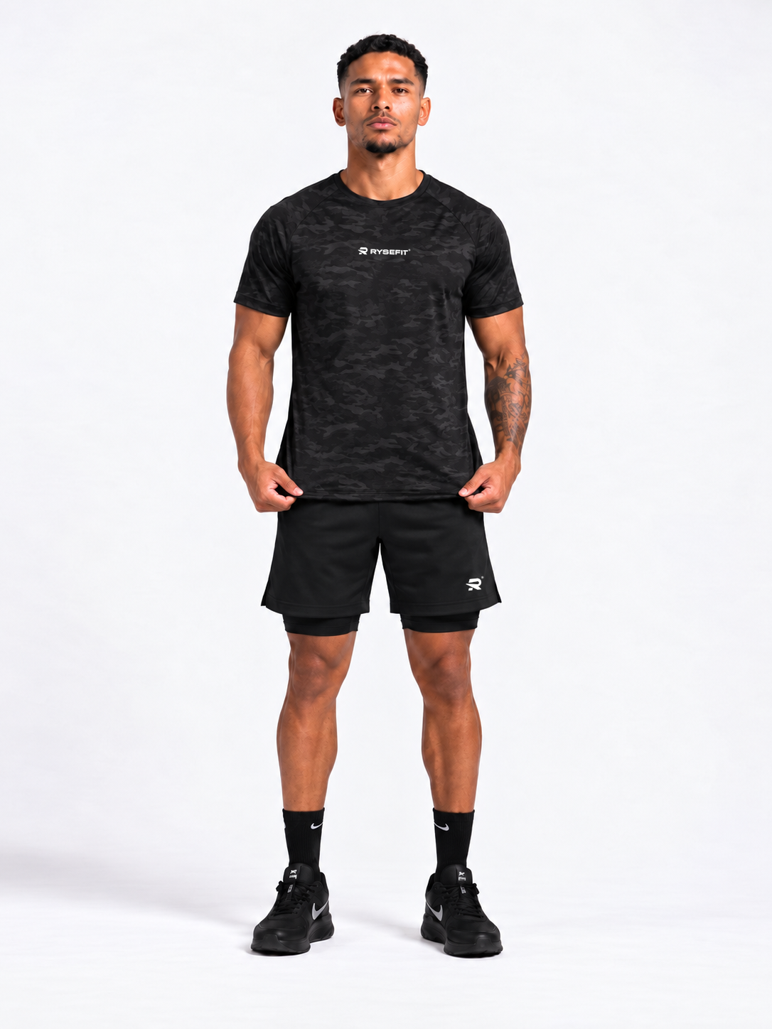 Rysefit Linha Stealth Preto: modelo de frente com camiseta camuflada preta e short preto